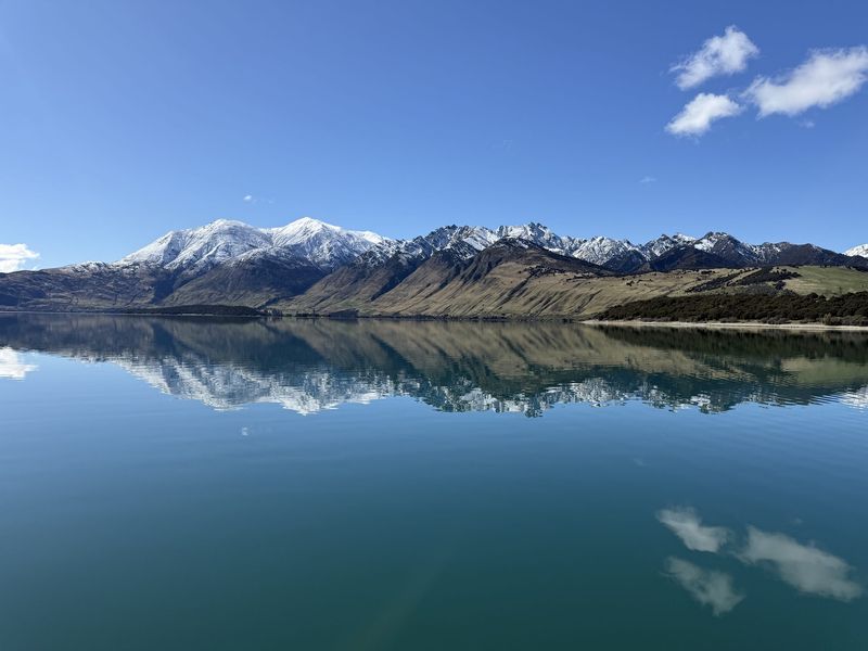 Snow-capped Southern Alps mirrored in Lake Hāwea's still water