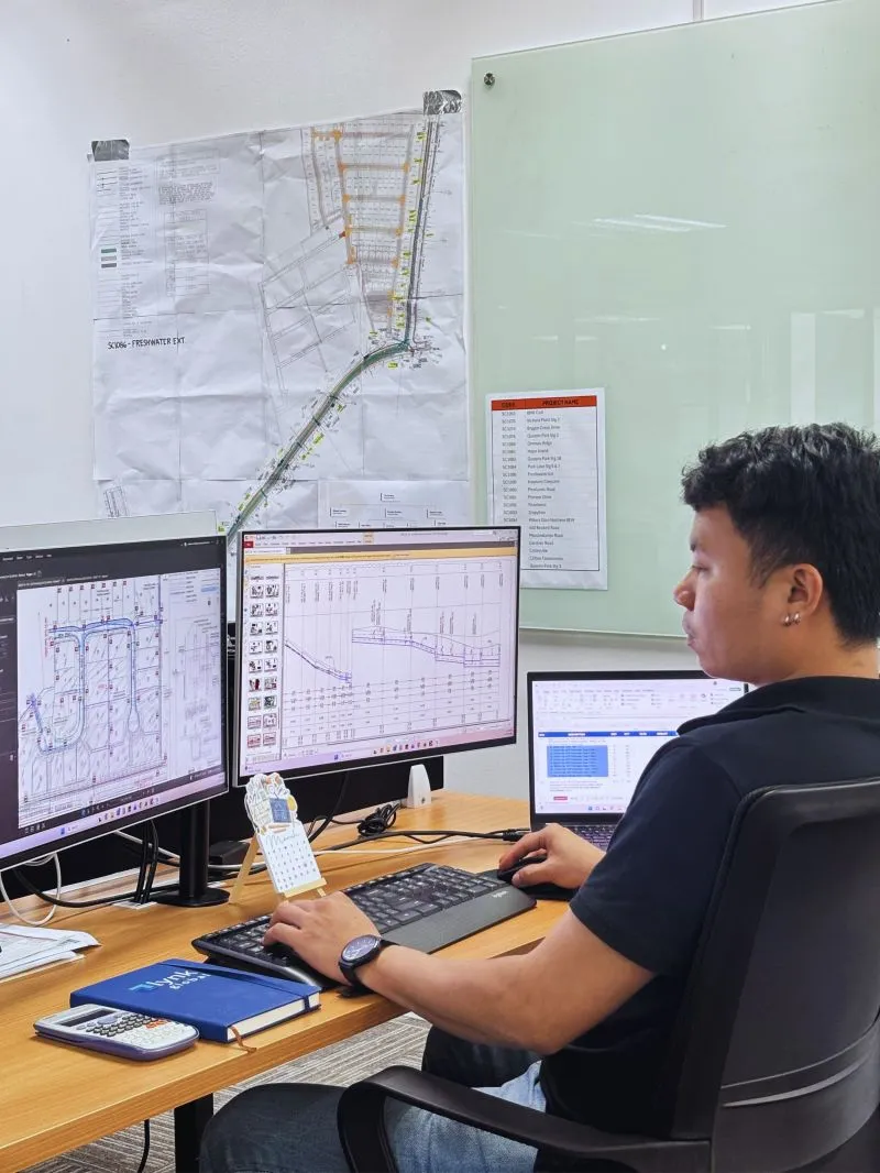 Lynk team member reviewing construction drawings at a dual-monitor workstation in Manila