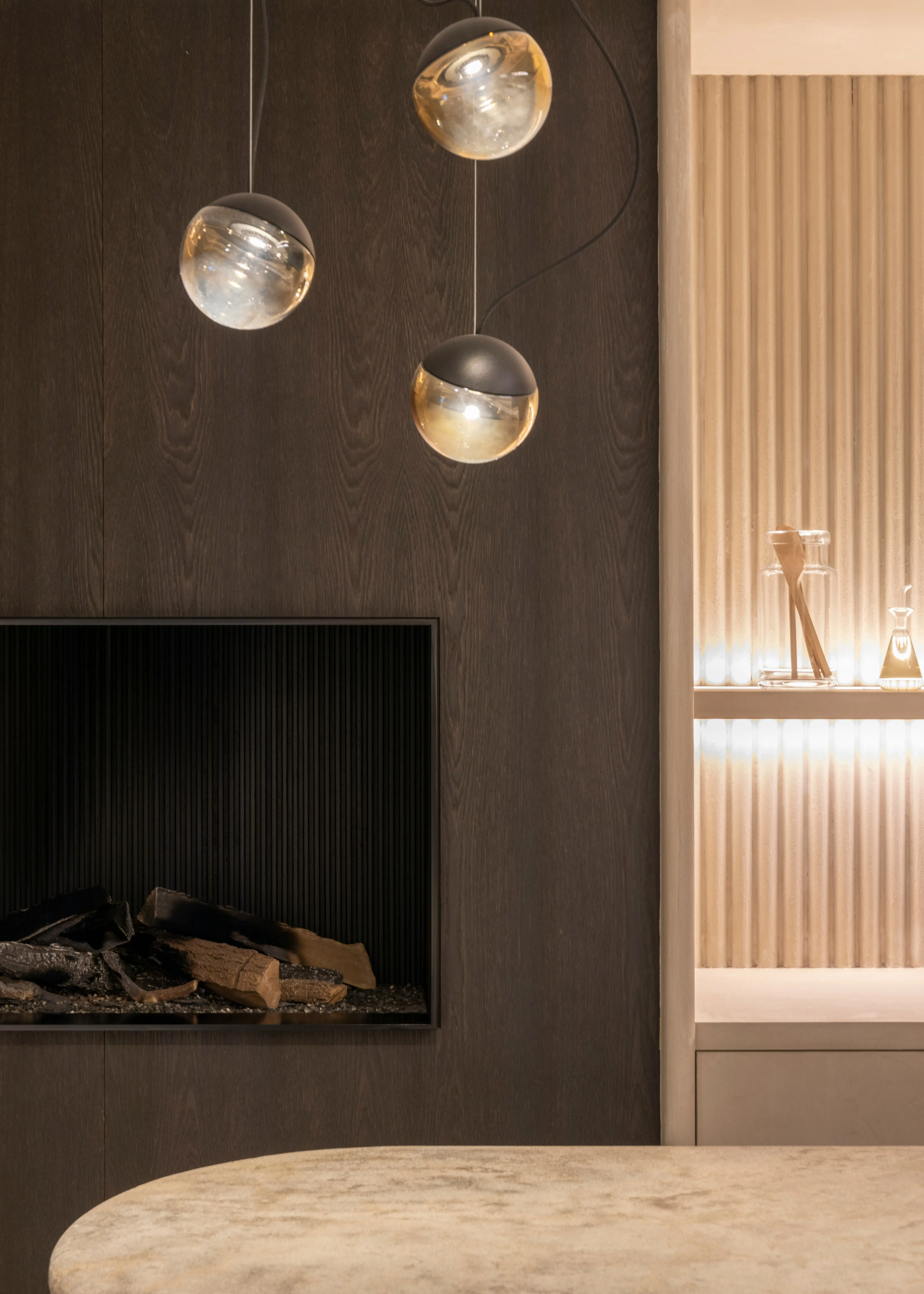 Dunkle Holzwand mit eingebautem Kamin und Glaspendelleuchten