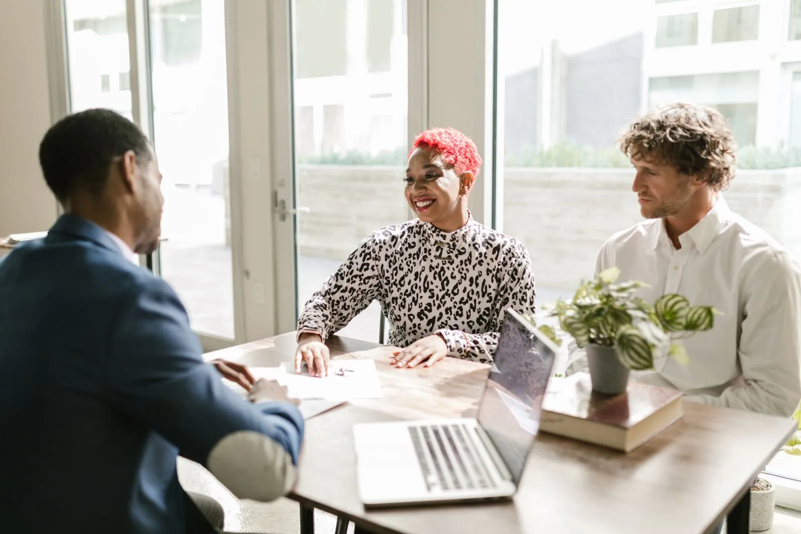 Financial advisor meeting with two small business clients in a bright office