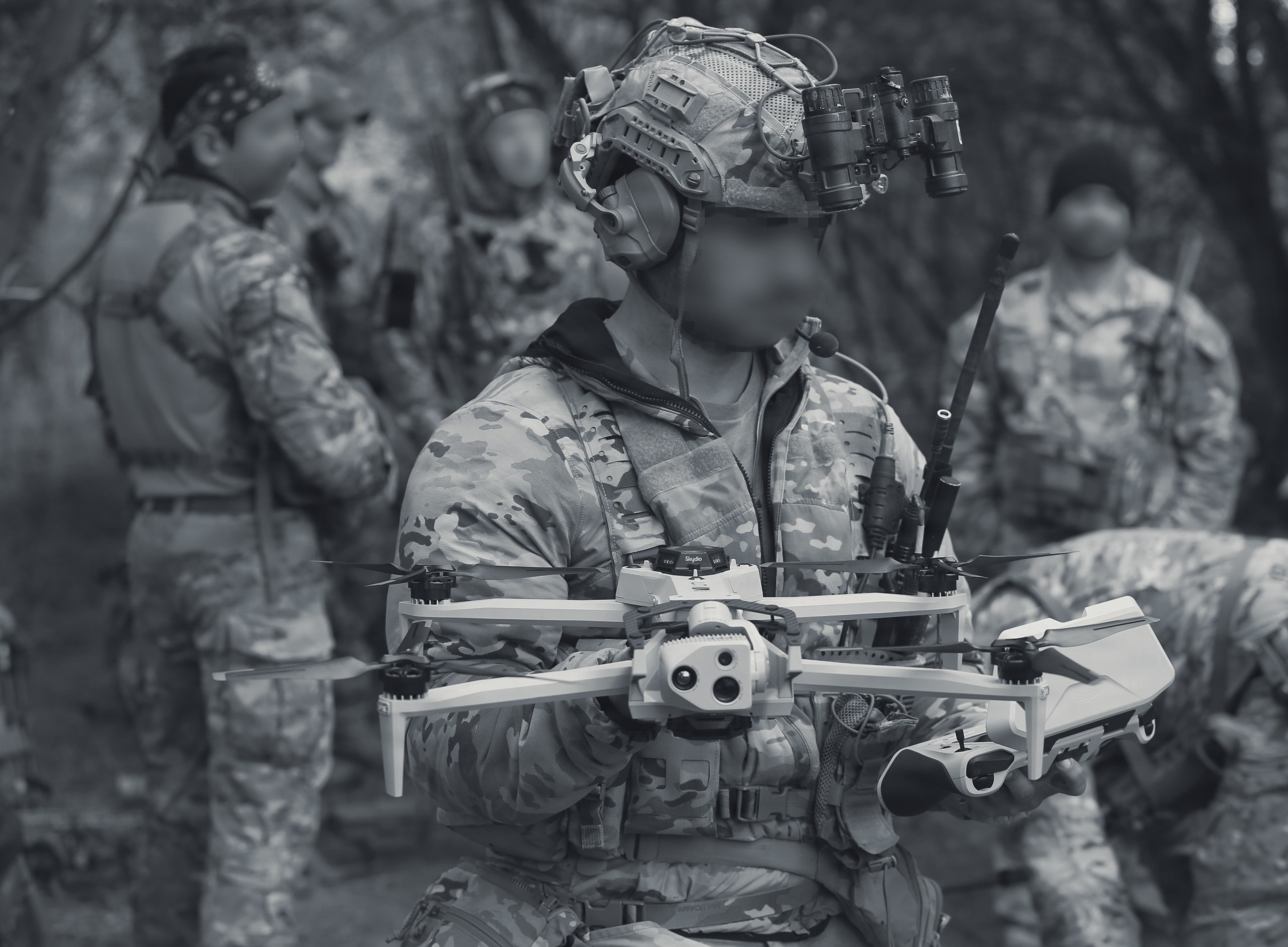 A warfighter holding a drone in the field