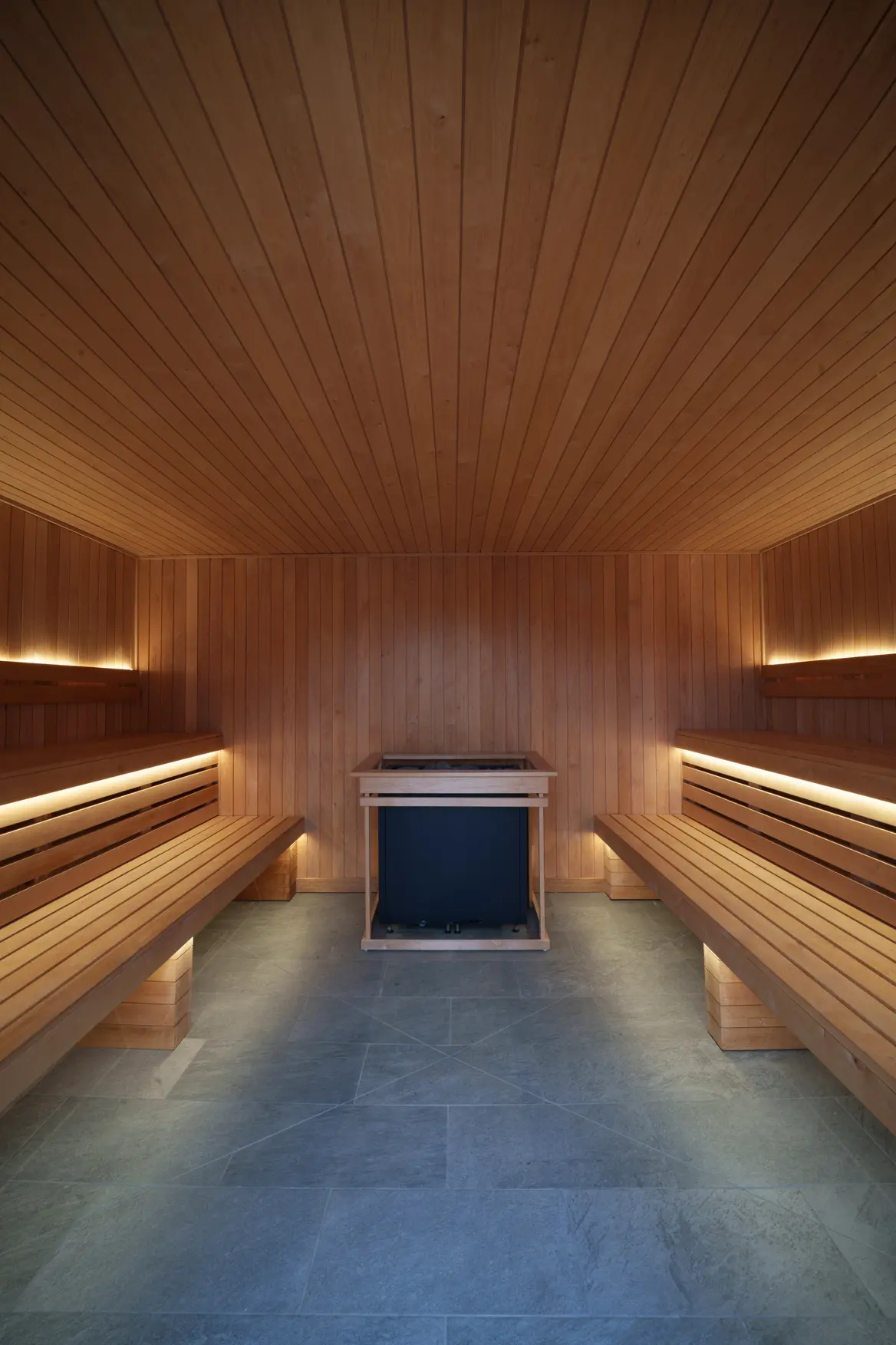 Long communal sauna with cedar benches and stone floor