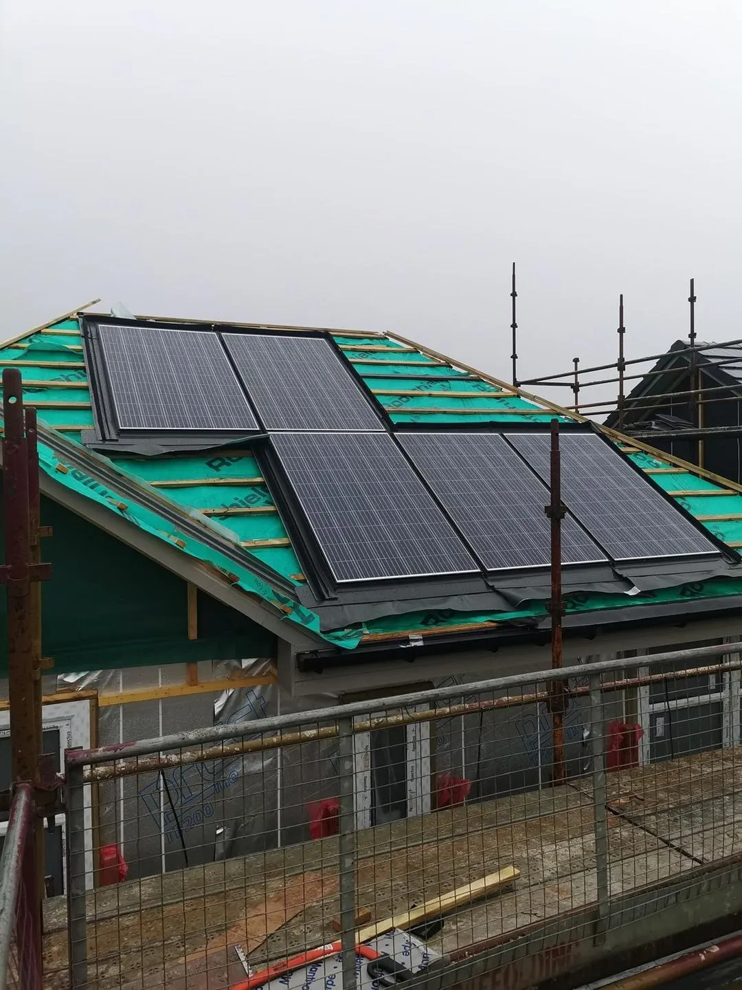Solar panels being installed on a large residential roof under construction