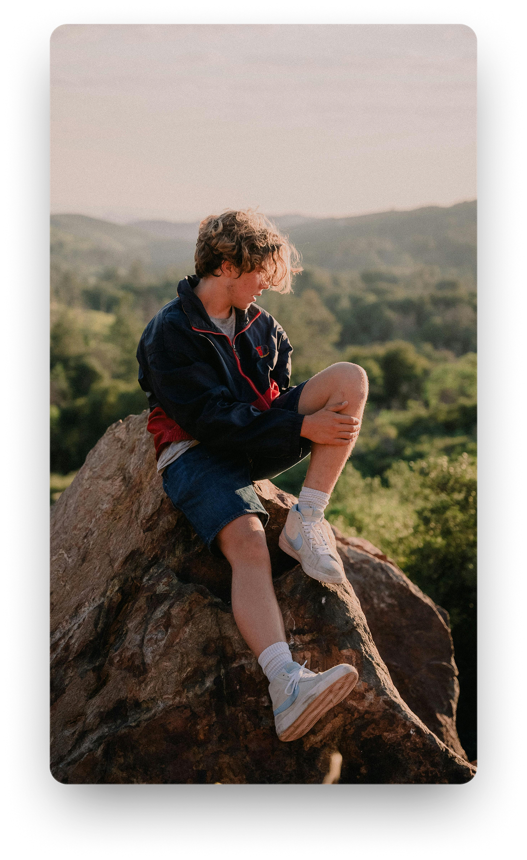 A person sitting on a rock looking out over the hills