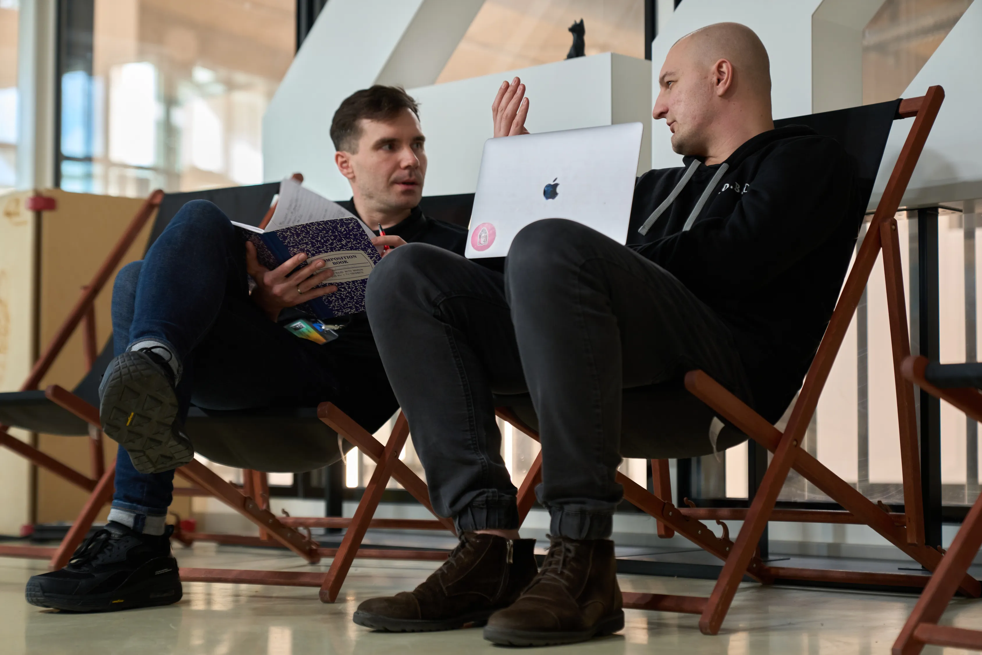 Two students talking in deck chairs on campus