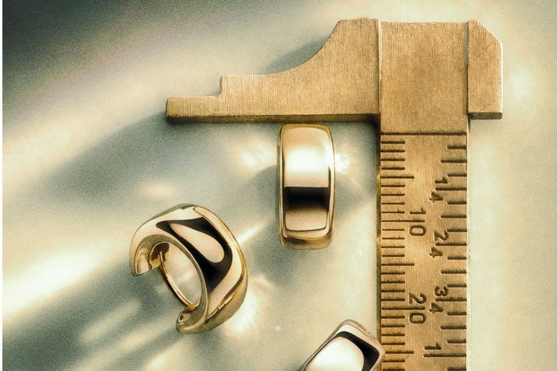 Gold earrings and a band beside a caliper