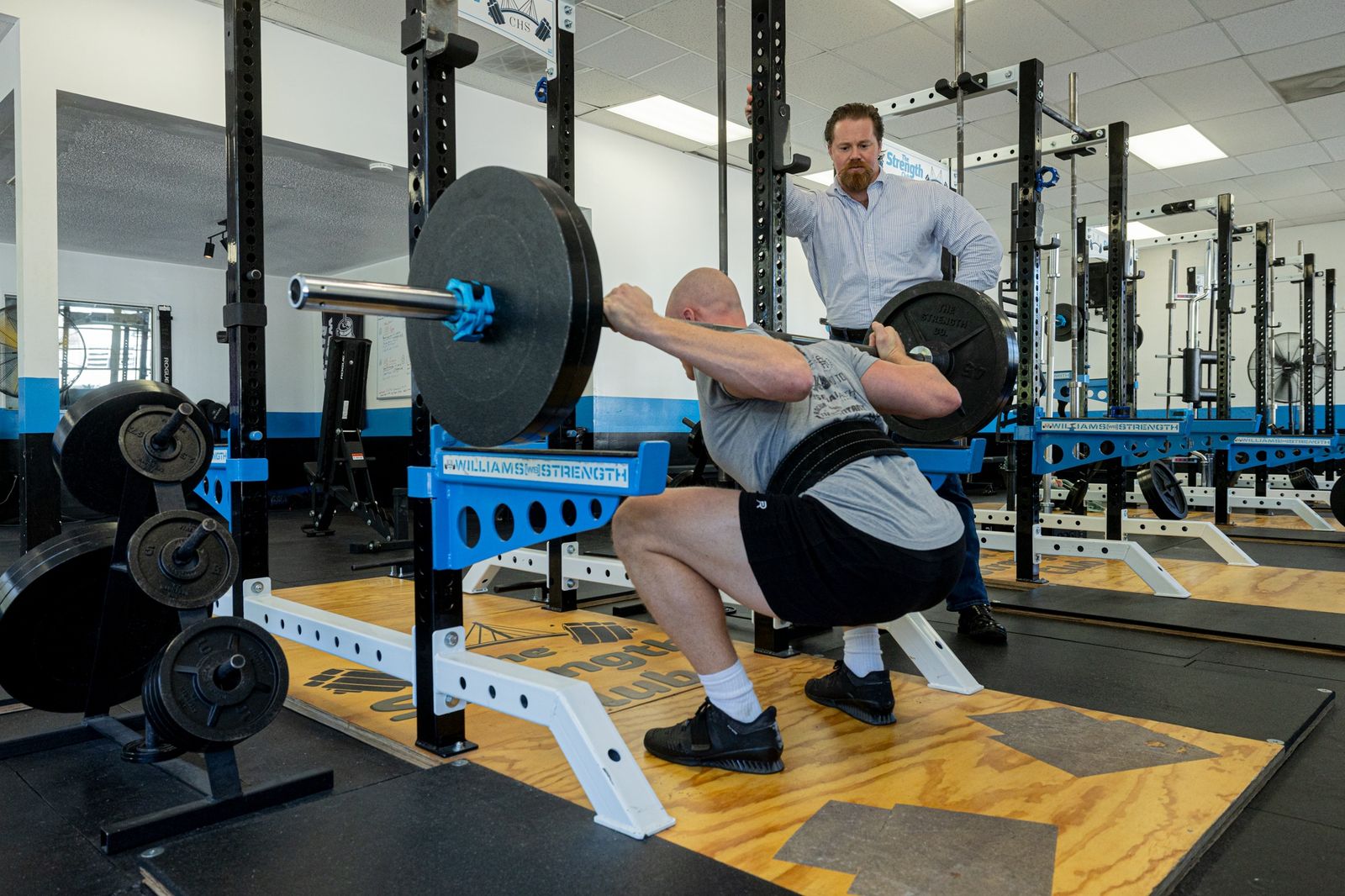 A Strength Club coach watching a member squat during a personal training session in Charleston