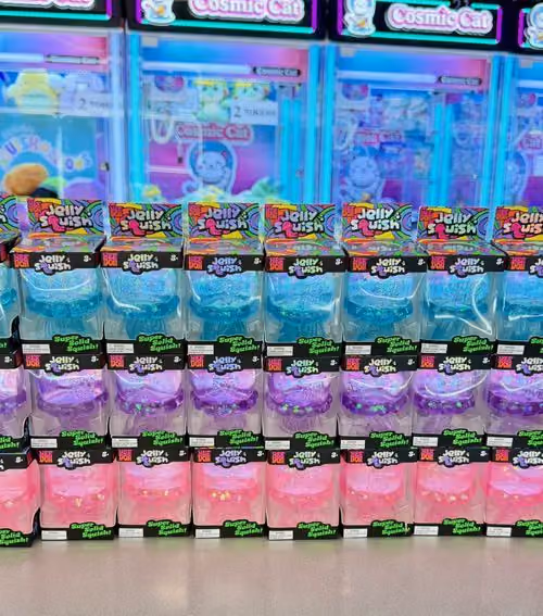 Rows of Jelly Squish squishies in blue, purple and pink in front of the claw machines