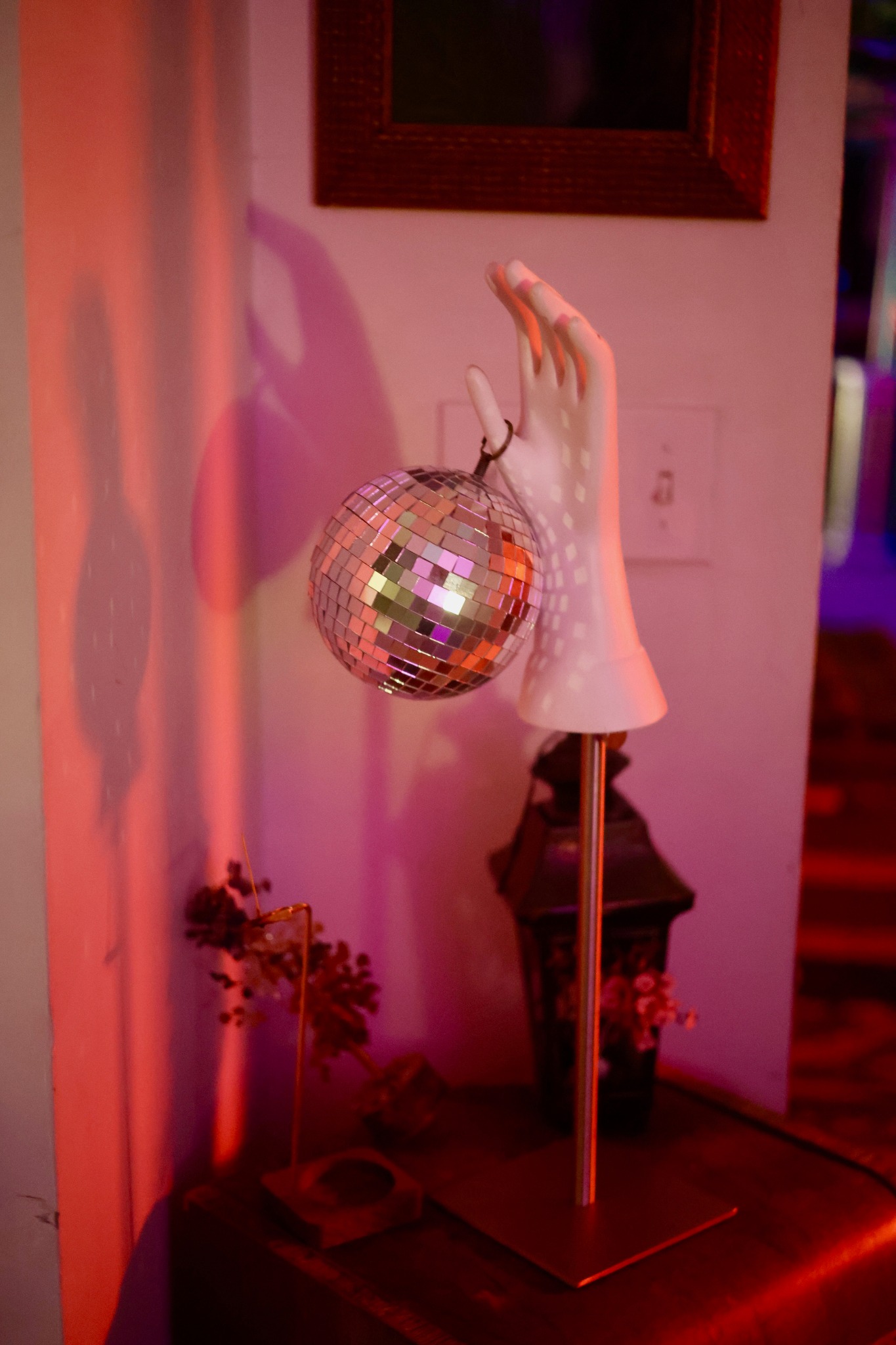 Sculptural white hand holding a small disco ball