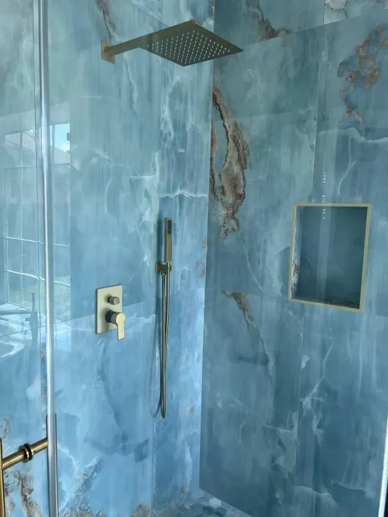 Blue onyx tiled shower with brass fixtures