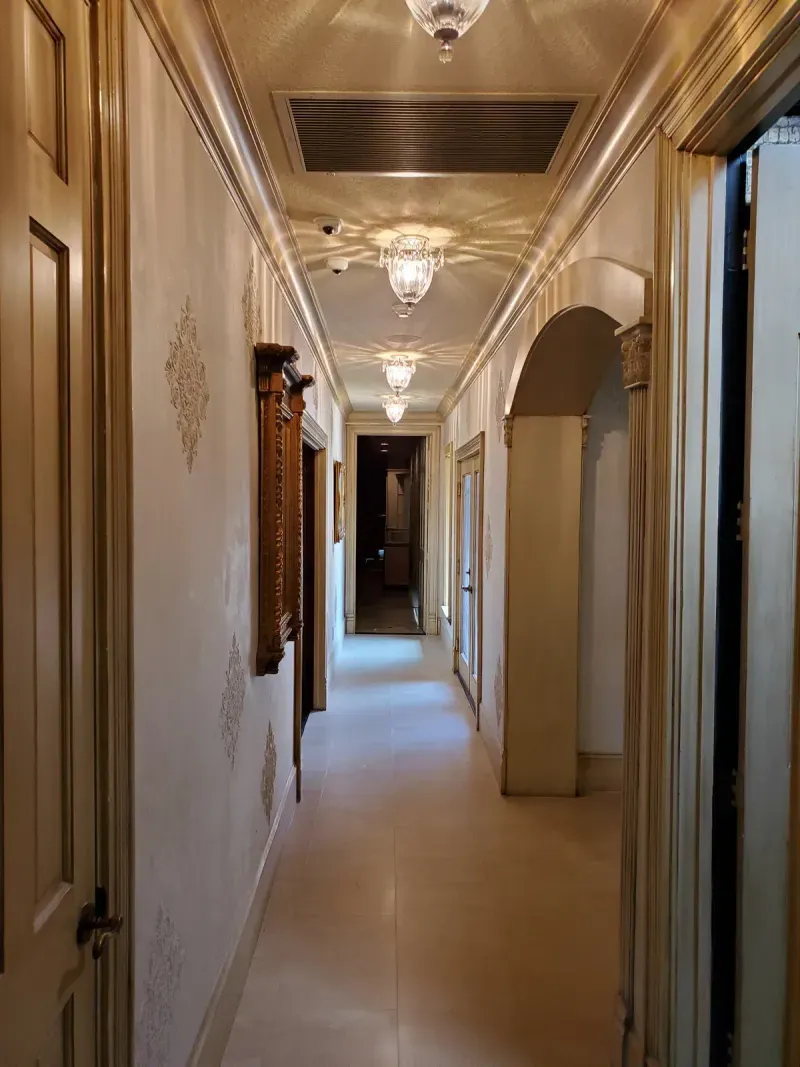 Elegant hallway with gold trim and crystal sconces