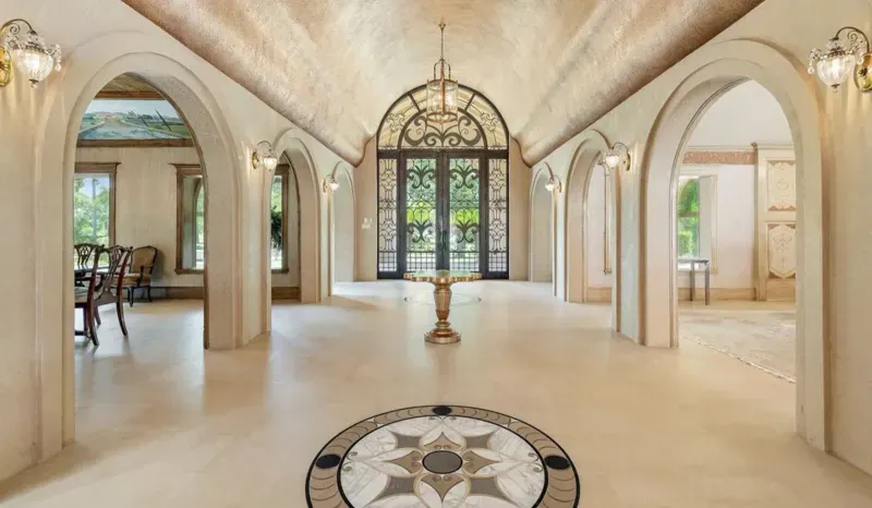 Grand foyer with arched iron doors and marble medallion floor