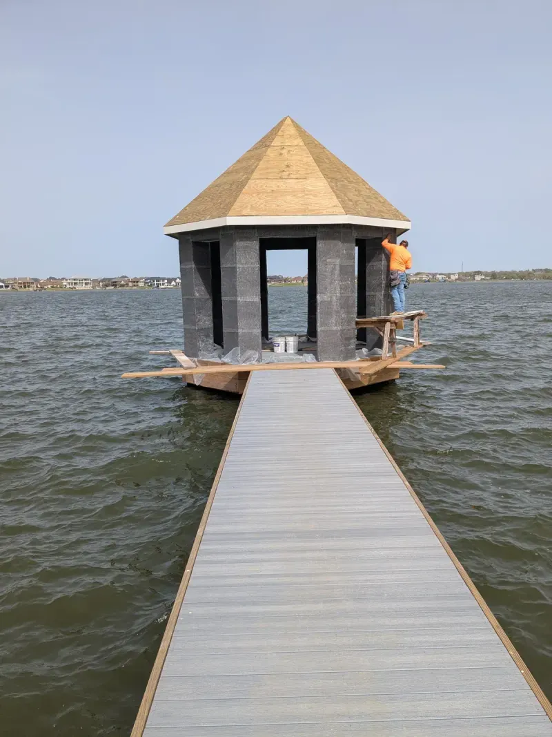 Worker installing roof on dock gazebo under construction