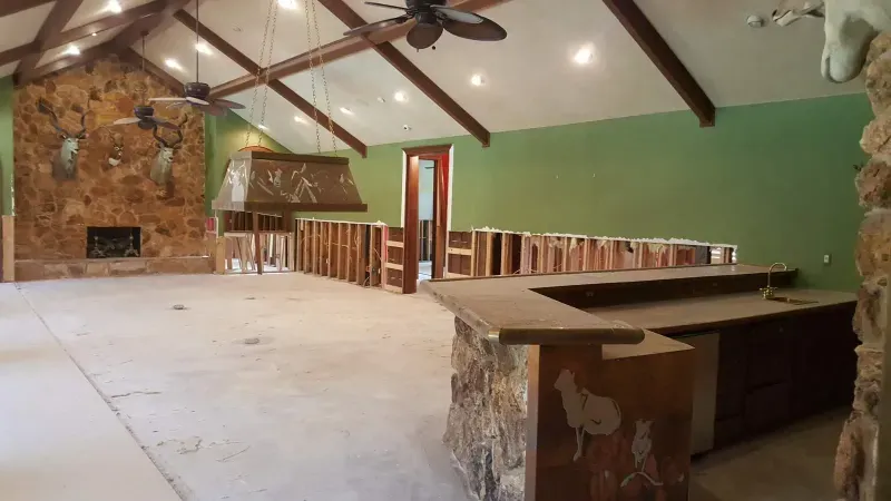 Game room mid-renovation with stone fireplace