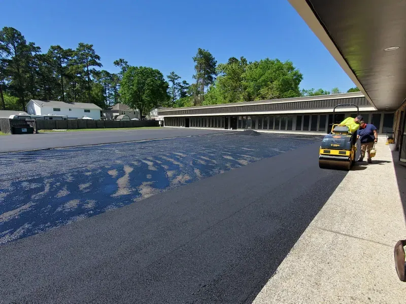 Crew resurfacing commercial parking lot with roller