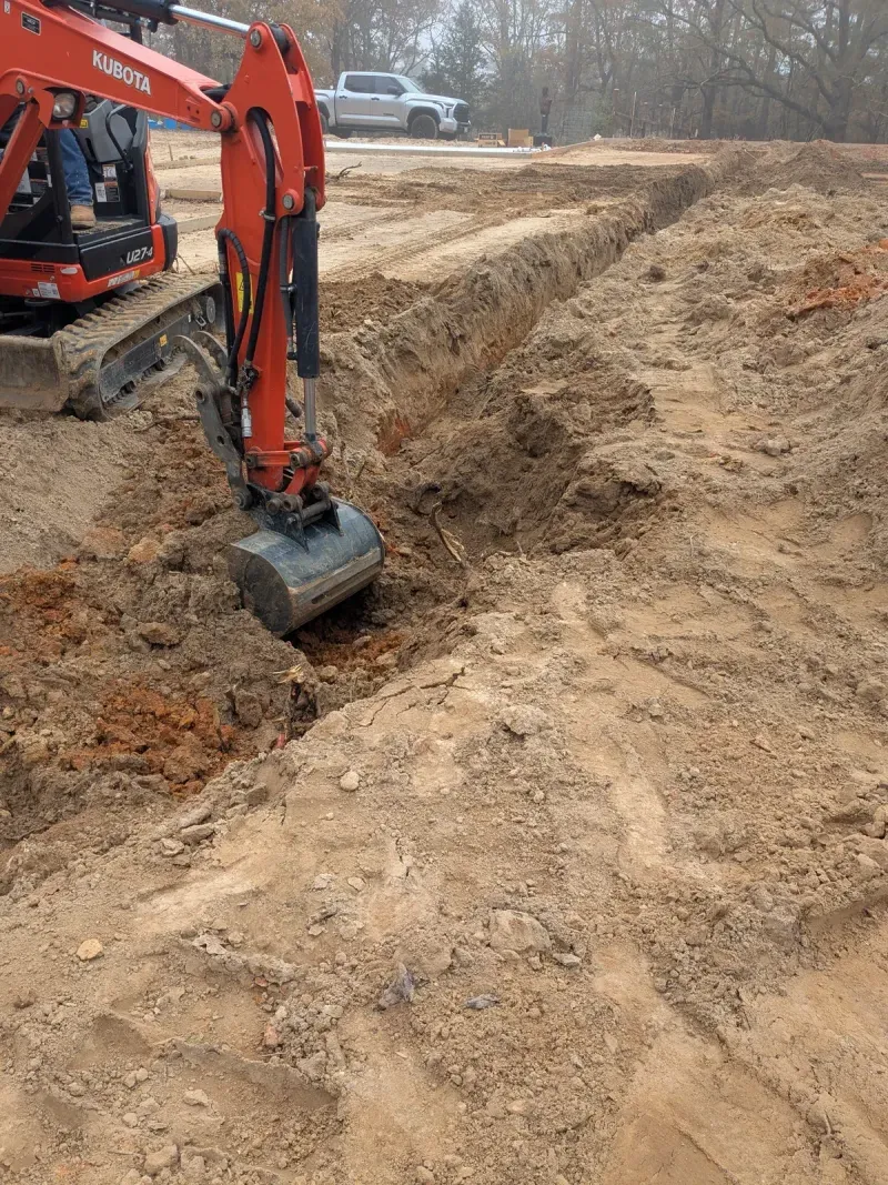 Excavator digging utility trench at commercial site