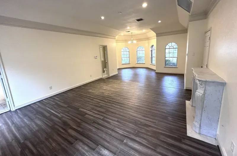 Great room with arched windows, dark wood flooring, and marble fireplace
