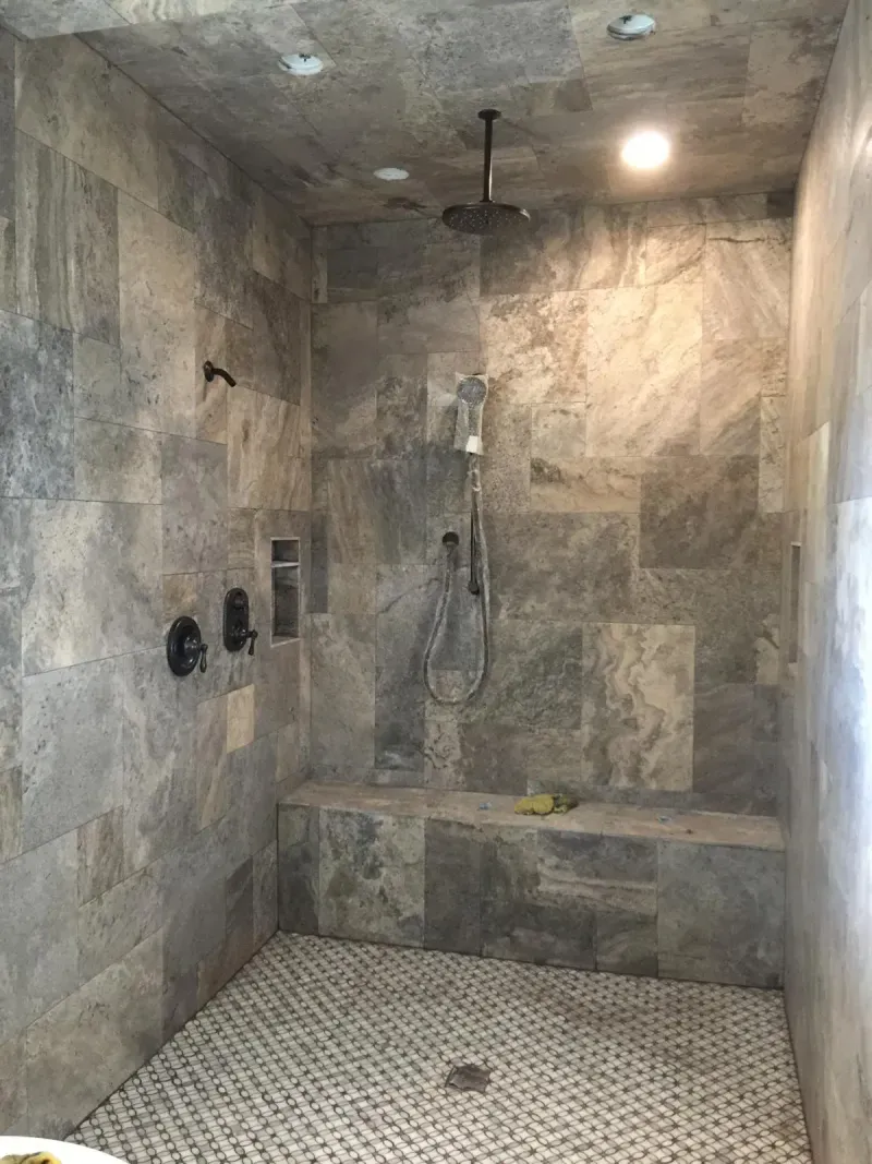 Custom stone tile shower with rain showerhead and bench