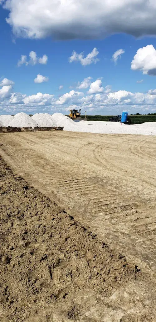 Bulldozer grading gravel base under blue sky