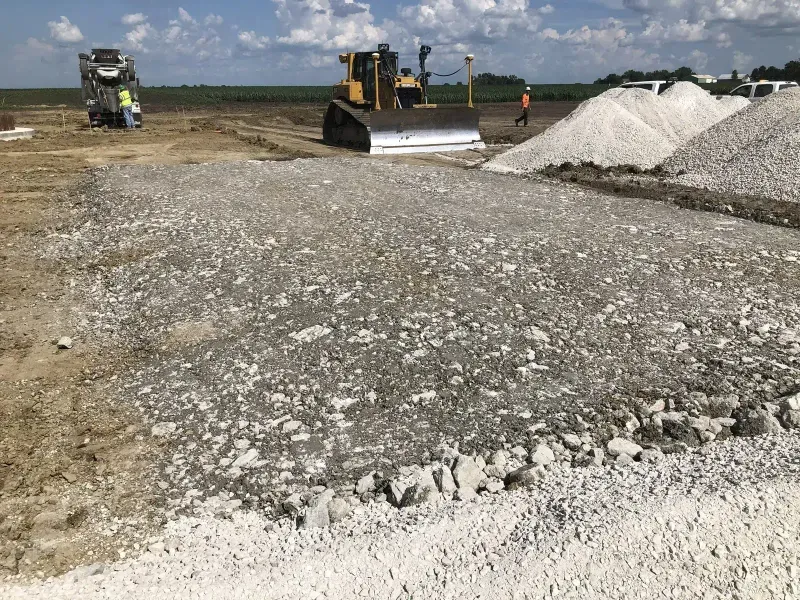 Bulldozer spreading gravel base with concrete truck on site