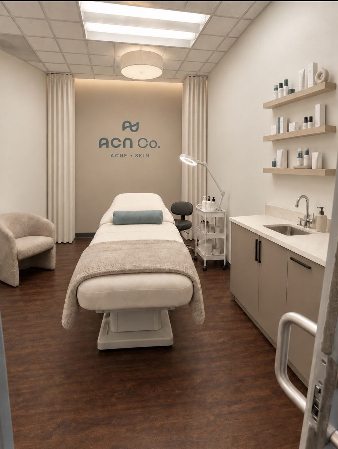 A calm treatment room with a treatment bed, privacy curtains and shelves of skincare products