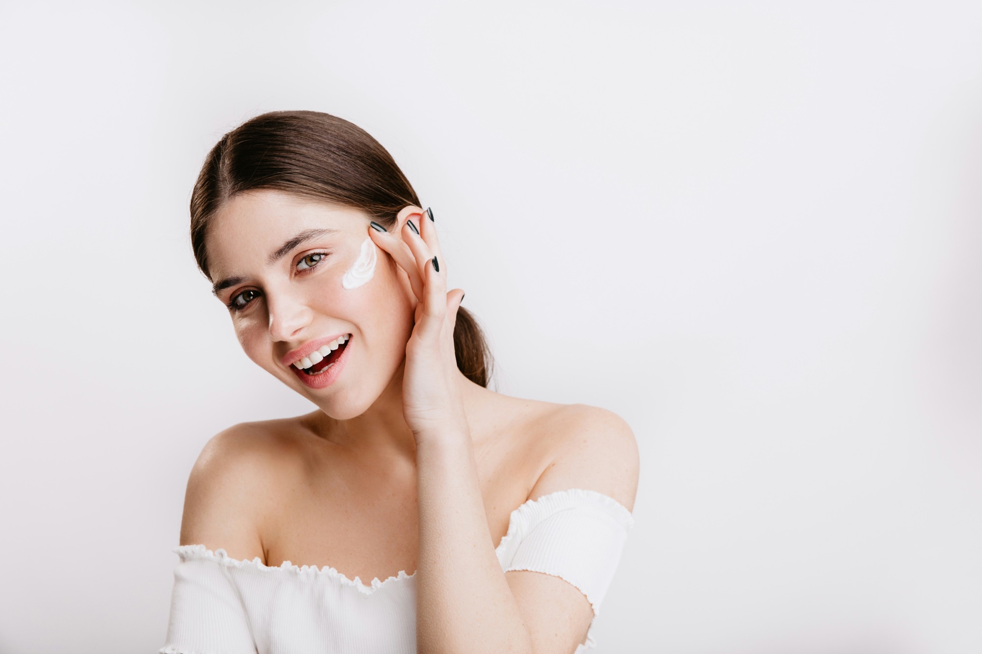 A person applying skincare to their cheek