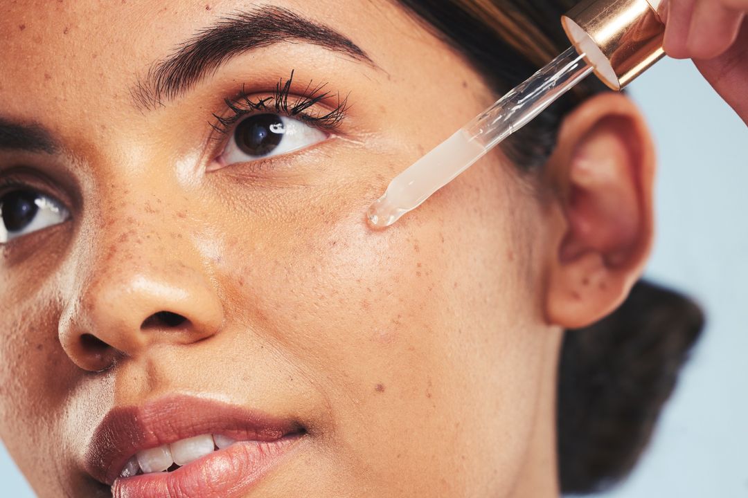 Close-up of a person’s face as a dropper touches the skin near the cheek