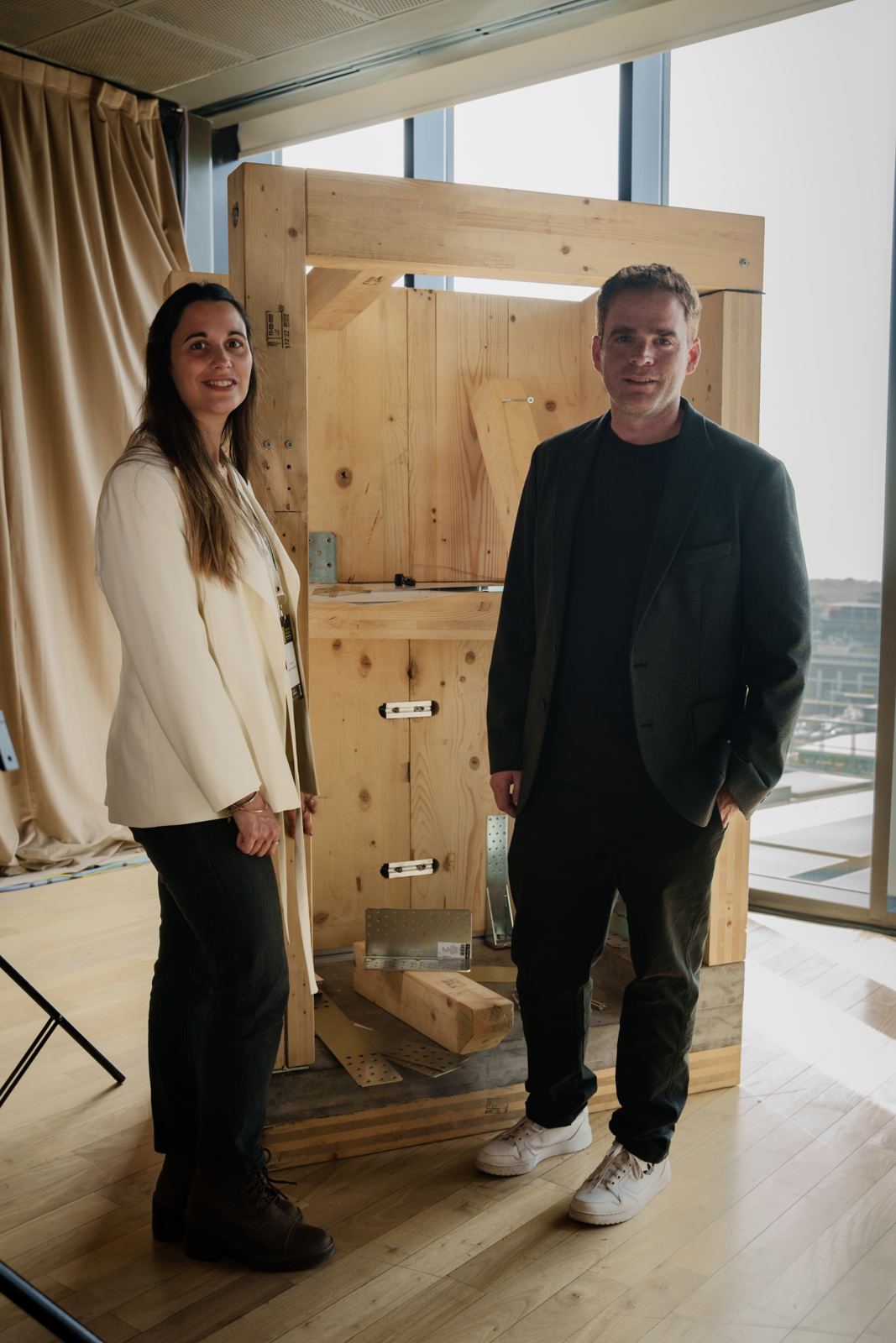 Dos visitantes junto a la maqueta de GLT y CLT en el espacio de Cambium.Build