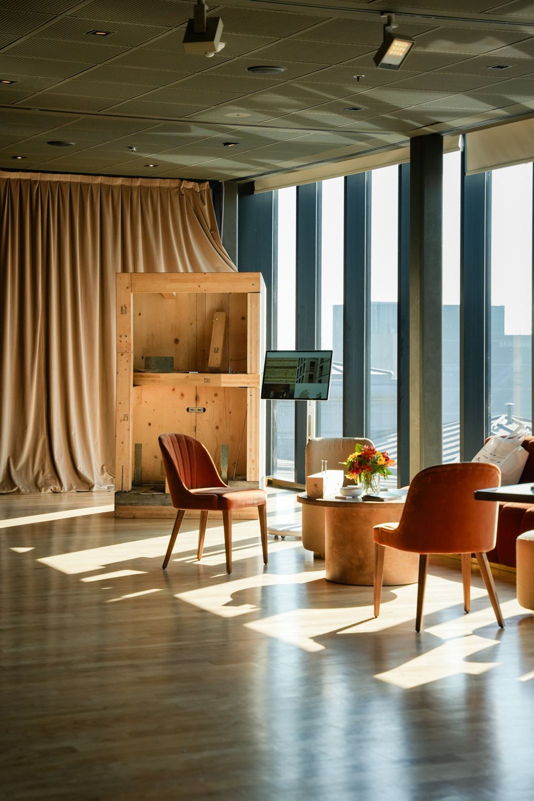 La maqueta de madera y la pantalla con imágenes del proceso constructivo, iluminadas por el sol