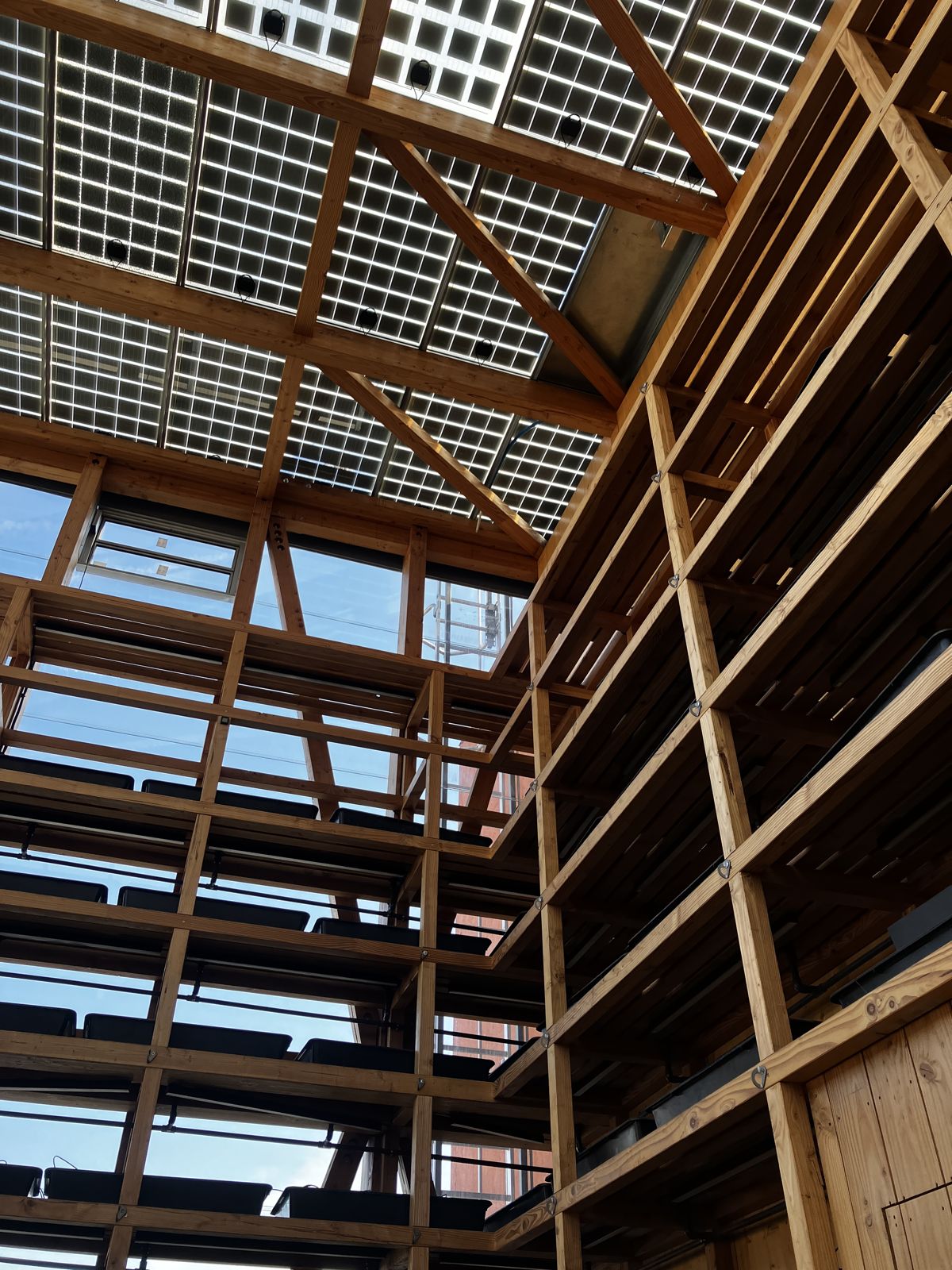 Estructura de madera del invernadero en cubierta, con paneles fotovoltaicos translúcidos y jardineras