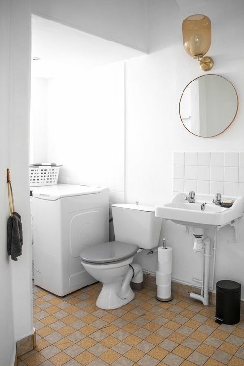 The toilet with hand basin and washing machine, on yellow patterned tiles