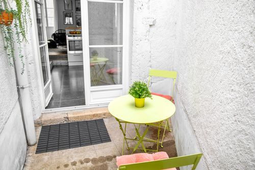 The small courtyard with a round table and colourful chairs, reached from the kitchen