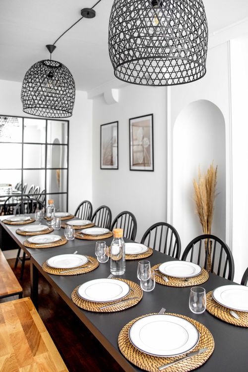 The large dining table set beneath black pendant lights