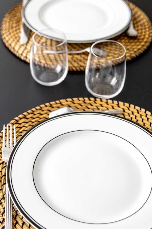 Detail of the table setting with white plates and woven placemats