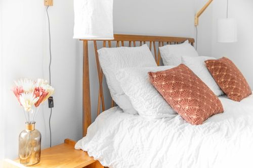 The double bed with a wooden headboard, terracotta cushions and bedside flowers