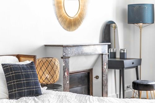 The bedroom’s decorative fireplace, gilt mirror and black dressing table