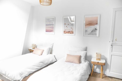The single beds with pink cushions and wall illustrations