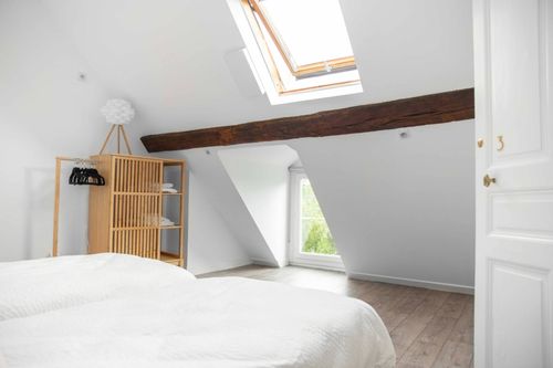 The attic bedroom with a roof window and exposed beam
