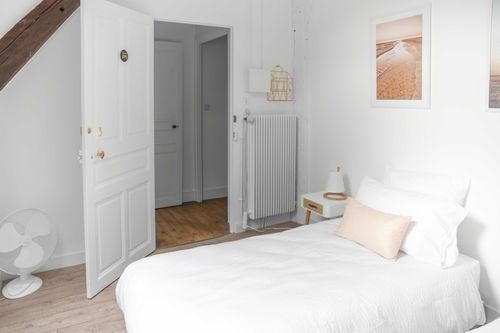 A single bed beneath a wooden beam in the attic bedroom