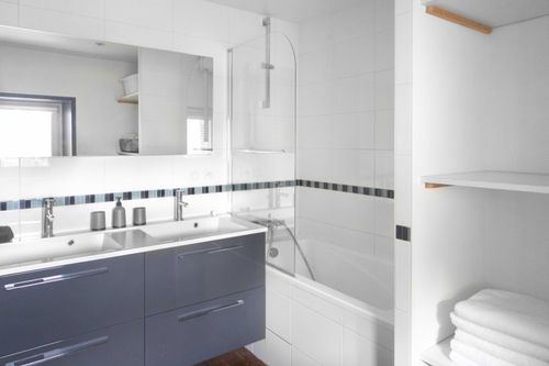 The bathroom with a bathtub, double basin and towel storage