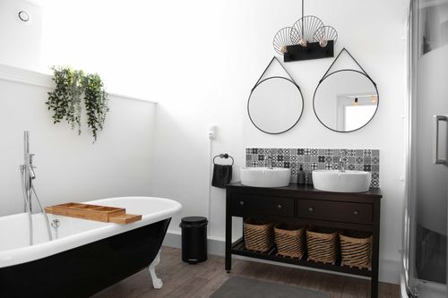 The bathroom with a clawfoot bathtub and two round basins
