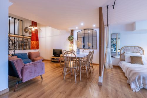 La Chambrée’s lounge with a sofa, round table and neighbouring sleeping area