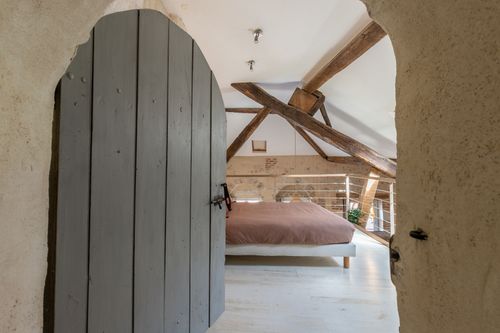 Le Loft’s mezzanine bedroom seen through an old arched doorway