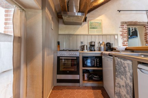 Le Loft’s kitchen beneath the beams, with a cooker and wooden worktops