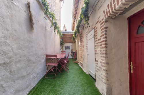 Les Chalands’ narrow courtyard with a table and chairs along the brick façade