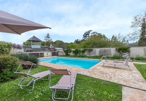 Sun loungers on the lawn beside the pool and parasol