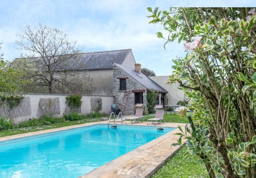 The pool bordered by stone and greenery in Le Cottage’s garden