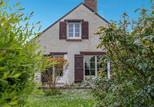 Le Cottage’s façade with burgundy shutters, framed by greenery