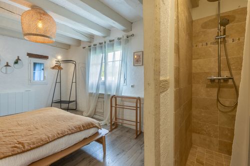 The bedroom with white beams and an adjoining shower