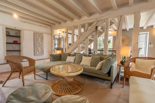 The lounge with armchairs around the sofa, in front of the wooden staircase